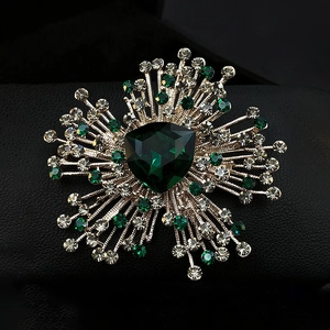 Luxurious emerald crystal flower brooch with shimmering rhinestones on black background