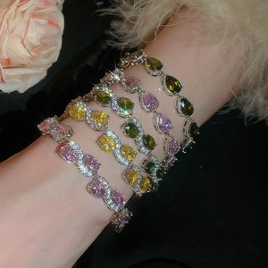 Macro detail of stacking bracelets with colorful teardrop and oval cut zircons on wrist