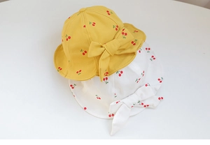 Close-up of yellow and white baby bucket hats with cherry print and bow details