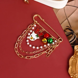 Christmas brooch with gold chains, red green bells and reindeer pendant on red background