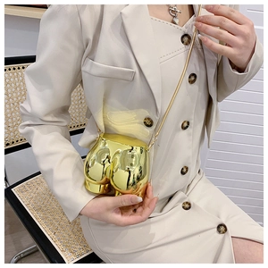 Detailed view of creative gold hip-shaped crossbody bag with a slim metal chain strap