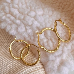 Elegant twisted S925 sterling silver hoop earrings in gold finish on knit fabric