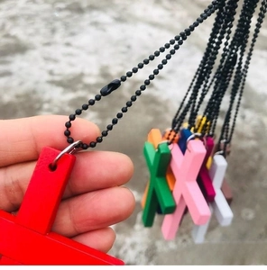 Macro shot of colorful wooden cross pendants with black beaded chain on a hand