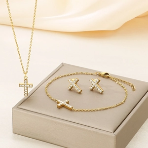 Close-up of gold-plated cross jewelry set with pavé crystals on a gift box