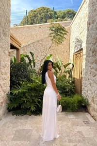 Elegant white sleeveless maxi dress featuring a low-back design and draped fabric detail