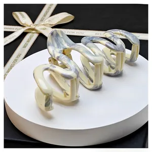 Detailed view of beige marble pattern claw clip on a display base with ribbon accent