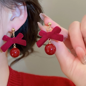 Gros plan de boucles d'oreilles nœud en velours rouge avec perle nacrée