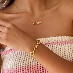 Détail d'un bracelet chaîne en O plaqué or 18K et collier love serti porté par un mannequin