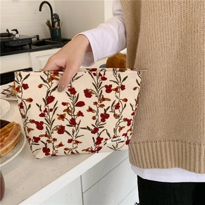 Détail de la trousse de maquillage vintage en velours côtelé à fleurs rouge et crème