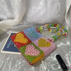 Top view of colorful beaded tote bag with heart pattern on silk background