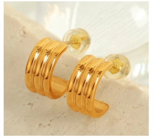 Vue macro de boucles d'oreilles en titane doré avec textures verticales à trois rainures