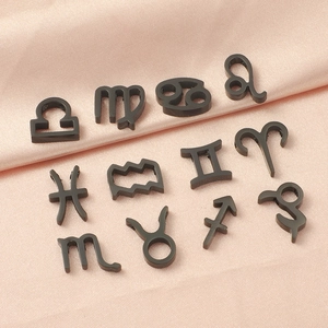 Detailed set of twelve black stainless steel zodiac sign charms on pink silk background