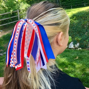 Detail of red white and blue American flag ribbon hair tie worn on a girl's ponytail