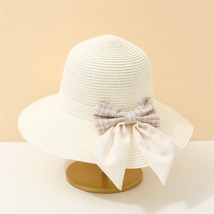 Straw sun hat for women with plaid bow and ribbon on a decorative gold stand