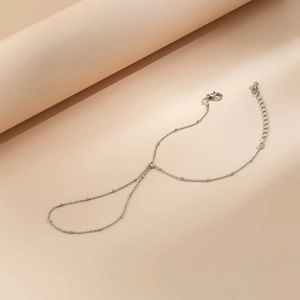 Detailed close-up of a silver slave bracelet with faux pearls and rhinestones on beige fabric