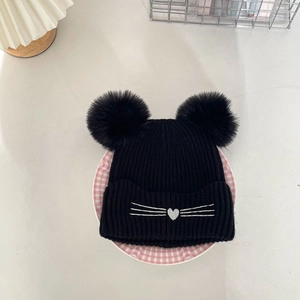 Detail of embroidered cat heart pattern and pom-poms on kids knit winter beanie