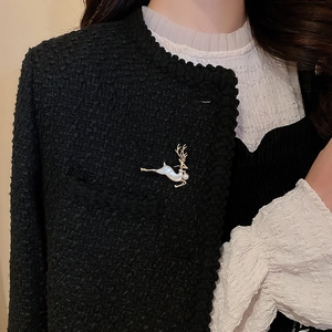Gros plan d'une broche cerf dorée avec nacre sur une veste en tweed noir élégante