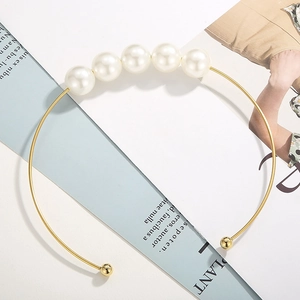 Elegant gold metal choker with five white pearls displayed on an open fashion magazine