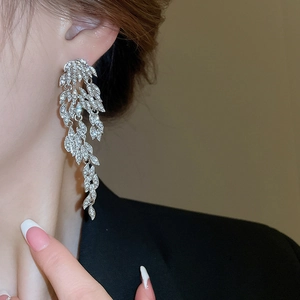 Close-up of long silver feather tassel earrings with sparkling crystals on model