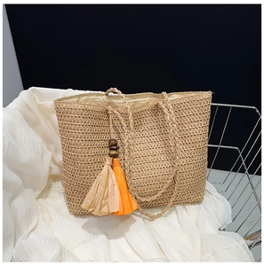 Detailed straw tote bag texture showing woven khaki fibers and double-colored tassel decor