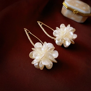 Dettaglio di orecchini a fiore perlato con ganci dorati e strass su velluto