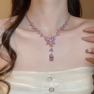 Detailed shot of pink crystal butterfly and teardrop tassel necklace on model neck