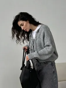 Gilet en maille grise avec fermeture à nœud porté avec un jean et un sac en cuir