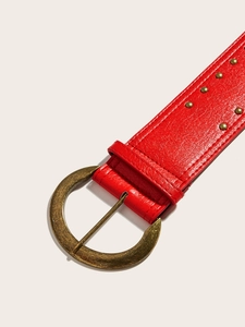 Détail d'une ceinture punk en cuir rouge avec boucle vintage et rivets dorés