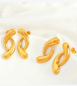 Detail of twisted S-shaped 18k gold plated stainless steel earrings on white silk