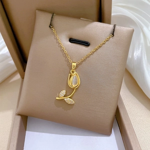 Detail of tulip pendant with cat eye stone and zircon accents on a gold chain