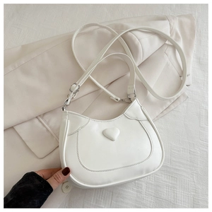 Detail of white saddle bag featuring a raised 3D heart and adjustable shoulder strap