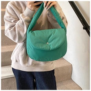 Detailed view of a vibrant green padded shoulder bag with a snap button closure worn by a model