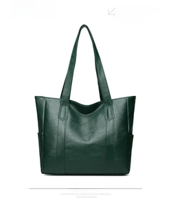 Detail view of the green tote bag showing smooth faux leather texture and side pockets