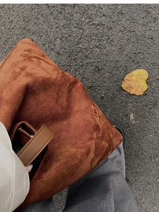 Caramel brown suede tote bag with matte texture on a street background with autumn leaves