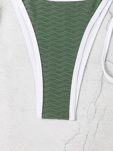 Macro view of dark green textured fabric with white piping on triangle bikini bottom