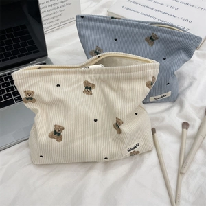 Detail of cream and blue corduroy makeup bags featuring cute embroidered bears