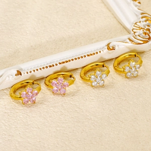 Elegant gold flower hoop earrings with pink and white cubic zirconia on a beige backdrop