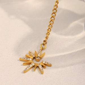 Macro detail of 18K gold plated starburst pendant with sparkling crystal accents