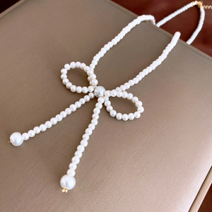 Detailed macro view of the bow-shaped pearl necklace featuring elegant long tassels