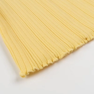Gros plan sur un tissu en maille côtelée jaune avec des détails de bordure ondulée