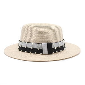 Detail of woven straw hat featuring black and white ribbon with pearls and rhinestones