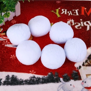 Close-up of six white plush snowball ornaments on a festive red Christmas carpet