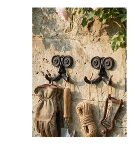 Detalle de ganchos de pared de hierro fundido con herramientas de jardín en pared