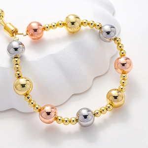 Macro shot of polished tricolor beaded bracelet with gold, silver, and rose gold finishes