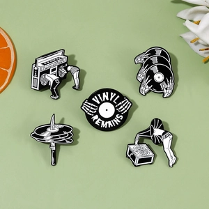 Close-up of retro music enamel pins set with vinyl and skull designs on green background