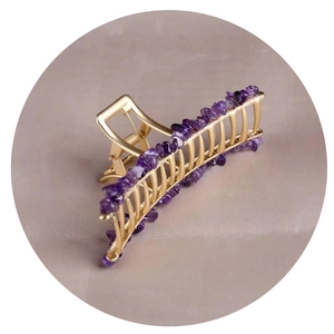 Golden alloy hair claw clip featuring natural purple crystal stones on a textured fabric