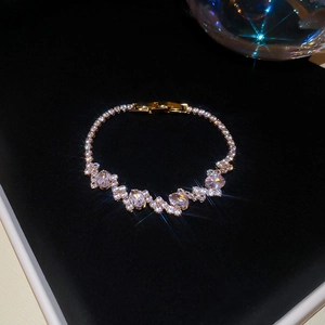 Close-up of gold-plated flower bracelet with sparkling zircons on black velvet background