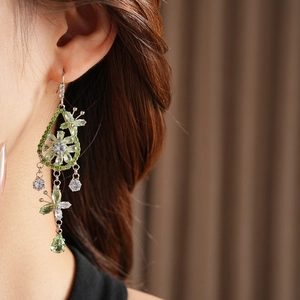 Model wearing long silver earrings with green zircon flower and teardrop pendants