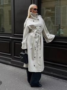 Detail view of cream long trench coat featuring double-breasted buttons and matching waist belt