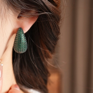 Gros plan de boucles d'oreilles vintage en forme de goutte avec zircone verte et métal noir